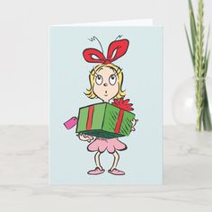 a greeting card with a cartoon girl holding a gift box in front of her face