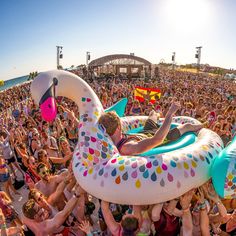 a large group of people on the beach with inflatable floats