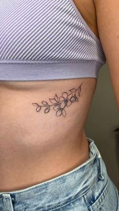 a woman's stomach with a flower tattoo on the side of her belly,