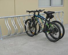 two bikes parked next to each other near a building with metal railings and windows