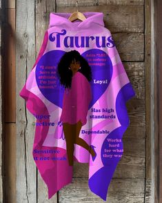 a woman's pink and purple towel hanging on a wooden wall with the words taurus written below it