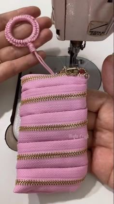 someone is working on a pink purse with gold chains and a sewing machine in the background