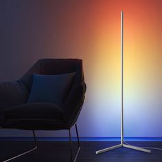 a black chair sitting next to a tall white floor lamp in a room with a rainbow colored wall behind it