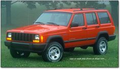 a red jeep parked on top of a lush green field in front of some trees