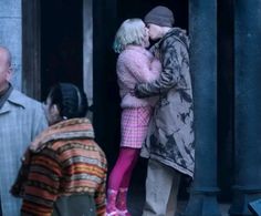 two people are kissing in the doorway of an old building with other people looking on