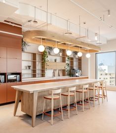 a kitchen with lots of counter space and lights hanging from the ceiling, along with bar stools