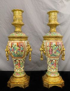 two ornate vases are sitting side by side on a black surface with a white background