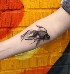 a woman's arm with a black and white tattoo of a goldfish on it