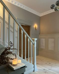 a room with white walls and wooden floors, two candles on the table next to an open door