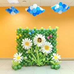 a balloon sculpture with daisies and balloons in the shape of a square, surrounded by clouds