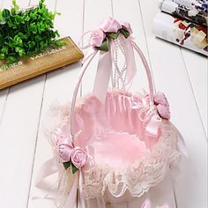 a small pink basket with flowers on the bottom and ribbon around it, sitting on a white table