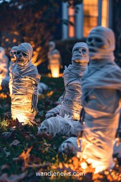 some fake skeletons are sitting in the grass with lights around them and one is wearing a ghost costume