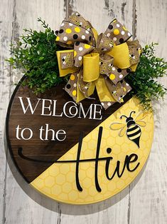 a welcome to the hive sign with a bow on it's head and a bee