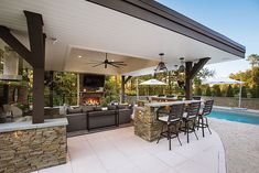 an outdoor kitchen and dining area next to a pool