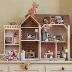 a doll house with furniture and accessories on top of the dresser in front of a wall