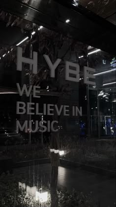 the reflection of a man standing in front of a sign that says hyb we believe in music