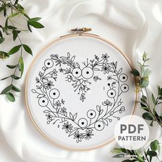 an embroidery pattern with flowers and leaves in the shape of a heart on a white background