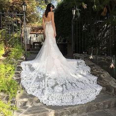 a woman in a wedding dress is standing on the steps looking down at her gown