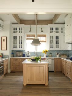 a large kitchen with wooden floors and white cabinetry on the walls, along with an island in the middle