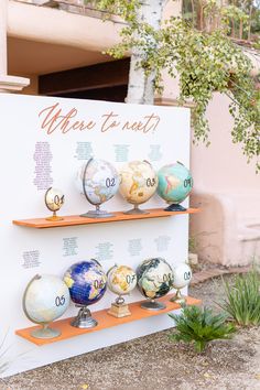 there are many different colored globes on the shelves in front of a sign that says where to eat