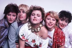 four women are posing together in front of a white background