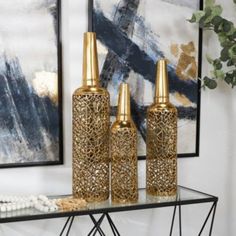 three gold vases sitting on top of a glass table