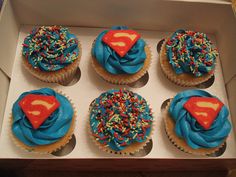 six cupcakes with blue frosting and sprinkles in a box