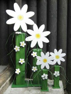 three green vases with white flowers in them