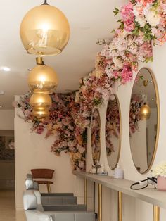 the interior of a hair salon with flowers on the wall and mirrors hanging from the ceiling