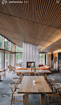 the interior of a restaurant with wooden tables, chairs and couches in front of large windows