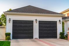 two black garage doors in front of a white house