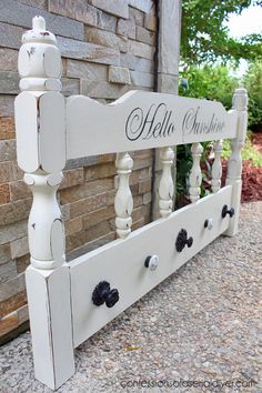 a white wooden bed frame with black knobs on it and the name hello sunshine painted on it