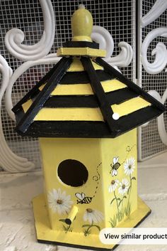 a yellow and black birdhouse with flowers painted on it