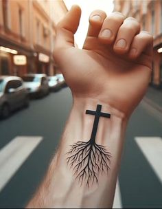 a hand with a cross and tree tattoo on it