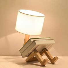 a lamp that is sitting on top of a wooden stand next to an open book