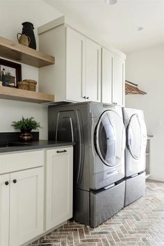 a washer and dryer are in the middle of a kitchen with white cabinets