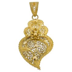 The "Viana's Heart" is a distinctive piece of jewelry originating from Portugal, specifically known for its intricate design and craftsmanship. This particular piece is crafted from 19 karat yellow gold, showcasing a rich and warm hue that adds to its elegance. The standout feature of the jewelry is its filigree work, a delicate and ornamental technique involving the use of fine, twisted threads of gold. Filigree is a traditional art form in Portuguese jewelry, and it involves skillful manipulat Portuguese Jewelry, The Sacred Heart Of Jesus, Filigree Heart, The Sacred Heart, Sacred Heart Of Jesus, Heart Of Jesus, Gold Filigree, Emerald Jewelry, Piercing Tattoo