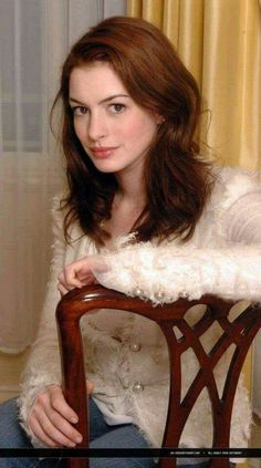 a woman sitting on top of a wooden chair