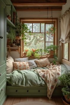 a bed sitting under a window next to a plant filled window sill with potted plants