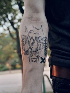 a man with a tattoo on his arm that has mountains and trees in the background