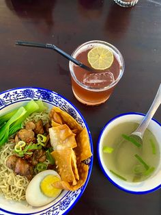 two bowls of food on a table next to cups of tea and drinks with chopsticks in them