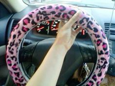 a person is holding their hand up to the steering wheel cover on a car that has pink and black cheetah print