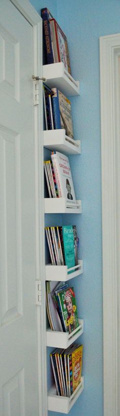 a white book shelf filled with books next to a blue wall in a room that has two doors open