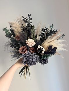 a hand holding a bouquet of dried flowers