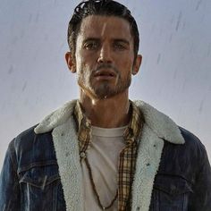 a man wearing a denim jacket standing in the rain