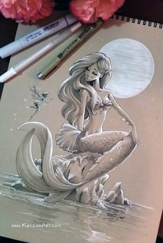 a drawing of a mermaid sitting on top of a table next to flowers and pencils