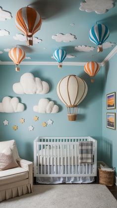 a baby's room with hot air balloons on the wall and clouds in the ceiling