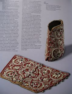 an ornate red and gold brocade on display next to a book with text in it