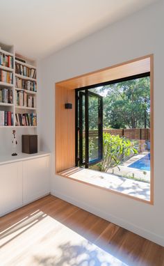 a room with bookshelves and a pool in the middle is seen through an open window