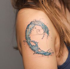 a woman's shoulder with a blue wave tattoo on her left arm and the letter q in it